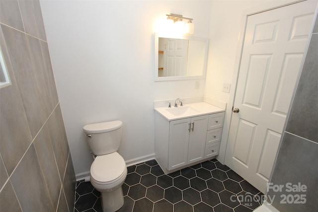 half bathroom featuring vanity, tile patterned flooring, and toilet