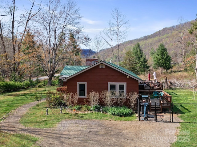 view of home's exterior featuring a yard, a deck with mountain view, and fence