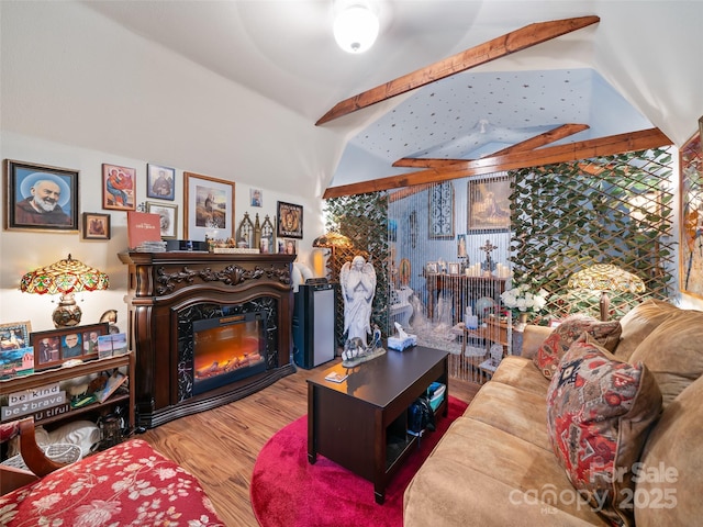 living area featuring lofted ceiling, a glass covered fireplace, and wood finished floors