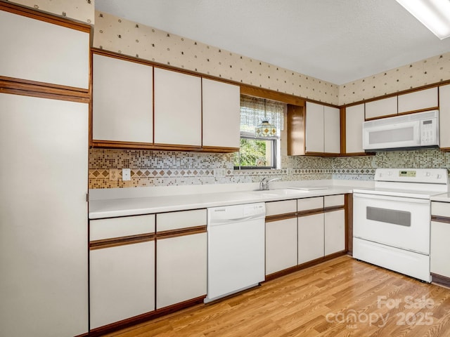 kitchen featuring tasteful backsplash, light wood-style floors, white cabinetry, white appliances, and light countertops