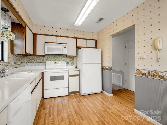 kitchen with visible vents, light countertops, white appliances, and light wood-style flooring