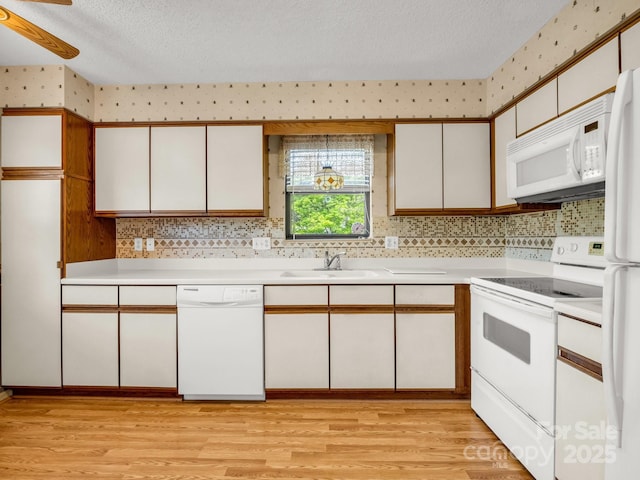 kitchen with light countertops, a sink, white appliances, and a textured ceiling