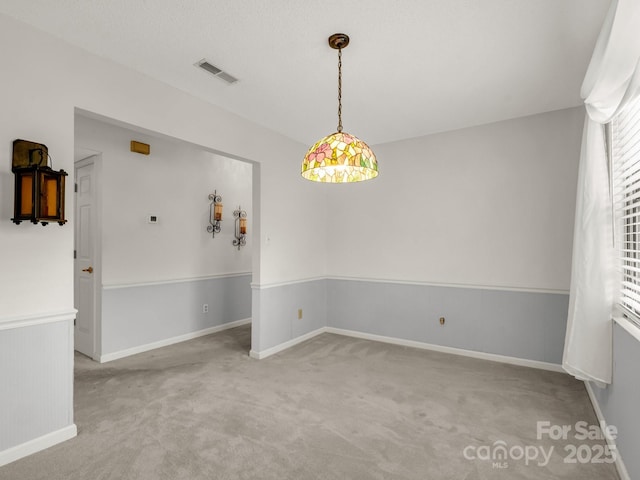 unfurnished dining area with baseboards, visible vents, and carpet