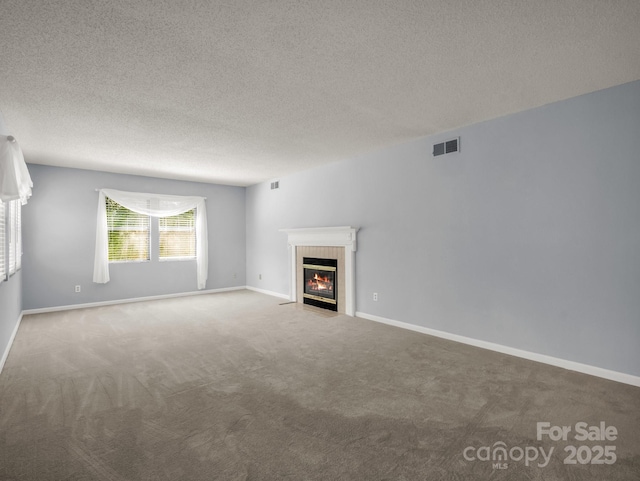 unfurnished living room with carpet floors, a textured ceiling, visible vents, and a tiled fireplace