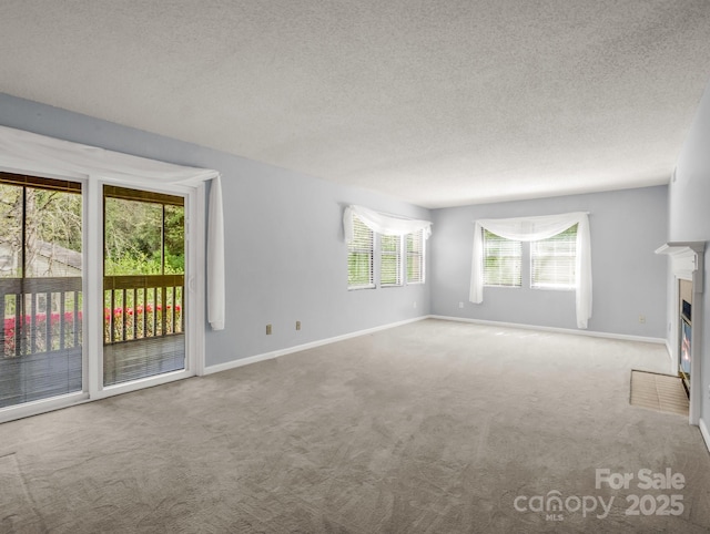 unfurnished living room featuring a fireplace with flush hearth, baseboards, and carpet flooring