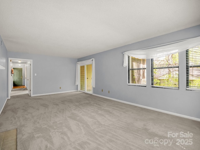 carpeted empty room featuring a textured ceiling and baseboards