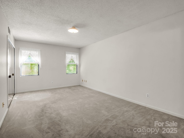 carpeted empty room with baseboards and a textured ceiling