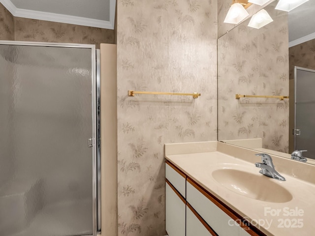 bathroom featuring crown molding, vanity, wallpapered walls, and a stall shower