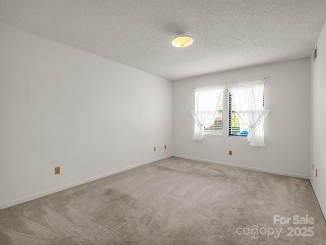 carpeted empty room featuring a textured ceiling, baseboards, and visible vents