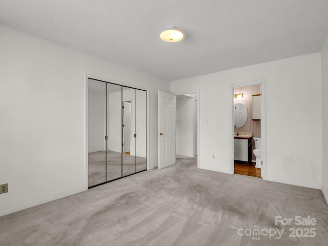 unfurnished bedroom with baseboards, carpet flooring, ensuite bathroom, and a closet