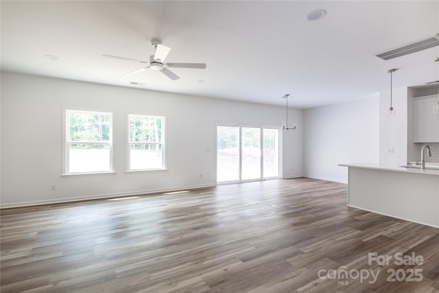 6223 Rockwell Blvd W, Charlotte, NC 28269 - unfurnished living room with a sink, visible vents, baseboards, wood finished floors, and ceiling fan with notable chandelier