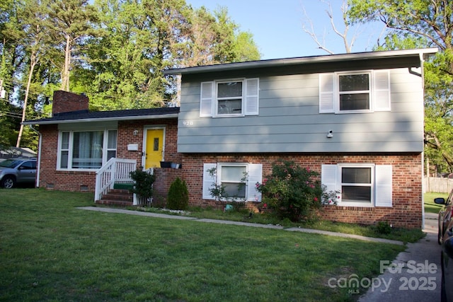 tri-level home with a chimney, brick siding, and a front yard