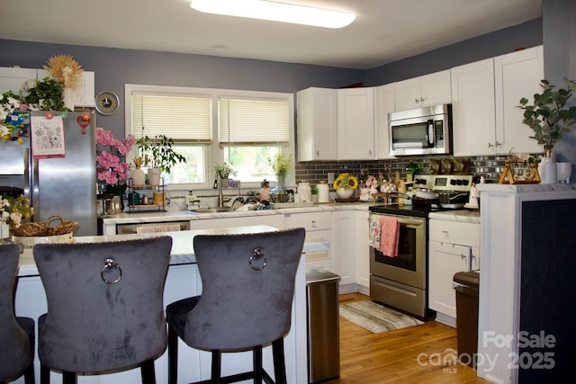 920 Squirrel Hill Rd, Charlotte, NC 28213 - kitchen featuring stainless steel appliances, white cabinetry, backsplash, a kitchen bar, and light countertops