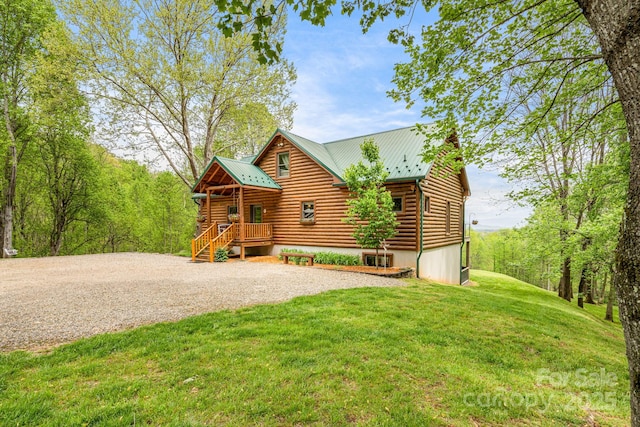 log-style house with gravel driveway, a front lawn, and metal roof