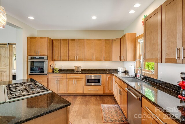 kitchen with recessed lighting, appliances with stainless steel finishes, dark stone counters, and a sink