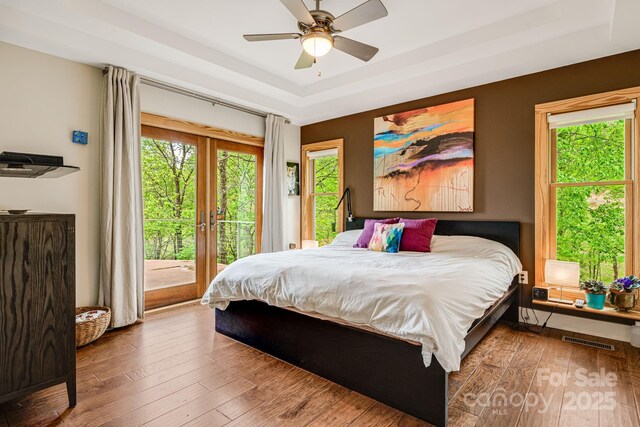 bedroom featuring multiple windows, hardwood / wood-style floors, and access to outside
