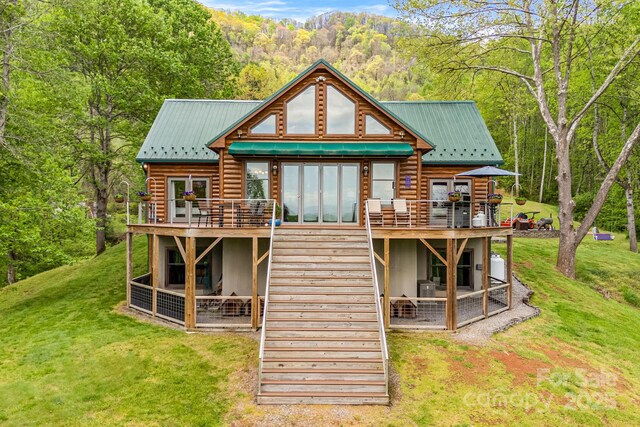 back of house featuring a wooden deck, a lawn, stairs, and metal roof