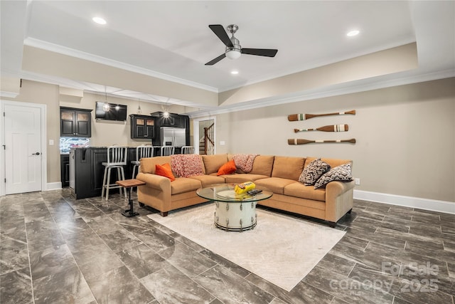 living area featuring a tray ceiling, ceiling fan, stairs, and ornamental molding