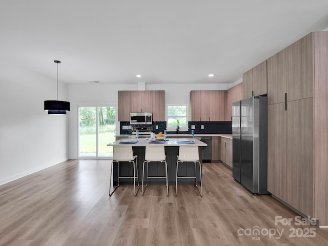 kitchen featuring plenty of natural light, a breakfast bar area, modern cabinets, light countertops, and stainless steel appliances