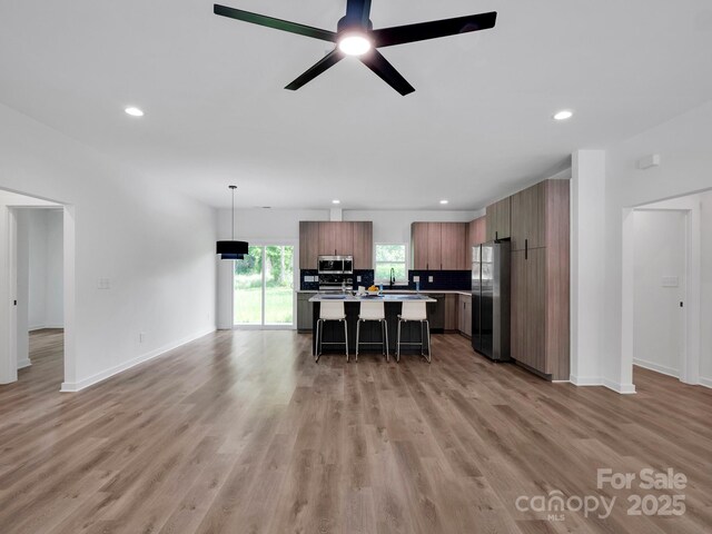 kitchen featuring a kitchen breakfast bar, a center island, recessed lighting, light countertops, and stainless steel appliances