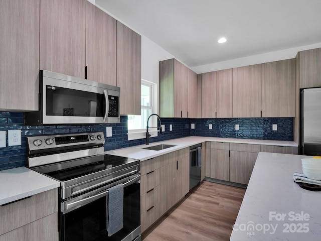 kitchen featuring light countertops, appliances with stainless steel finishes, a sink, and modern cabinets