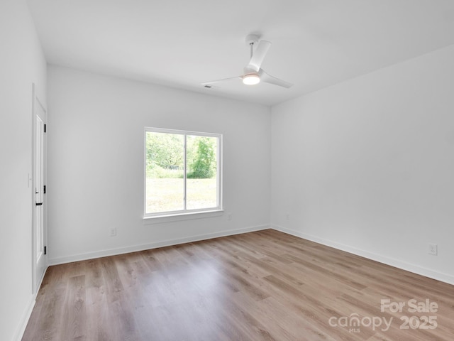 empty room featuring a ceiling fan, baseboards, and light wood-type flooring