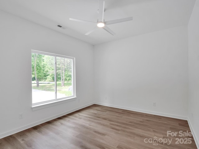 empty room featuring visible vents, baseboards, ceiling fan, and wood finished floors