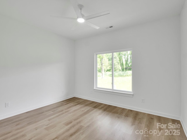 unfurnished room featuring a ceiling fan, baseboards, visible vents, and wood finished floors