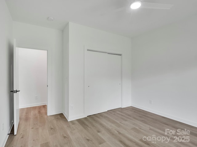 unfurnished bedroom featuring a closet, a ceiling fan, light wood finished floors, and baseboards