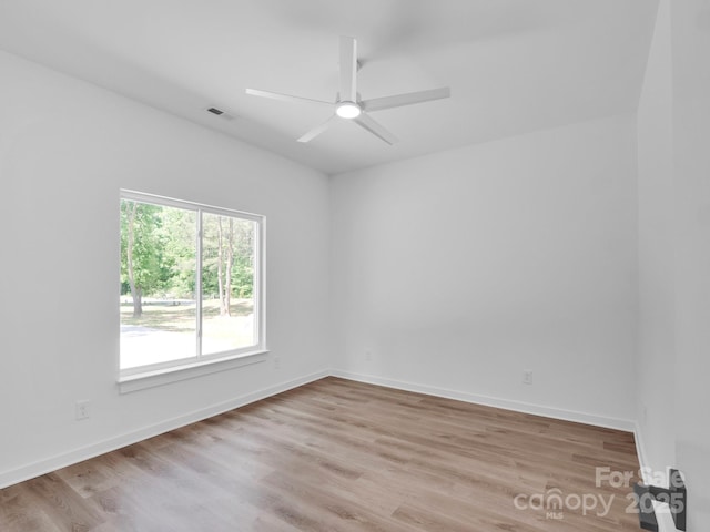 unfurnished room featuring a ceiling fan, baseboards, visible vents, and light wood-type flooring