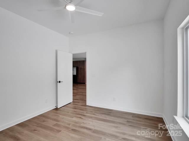 spare room with baseboards, a ceiling fan, and wood finished floors
