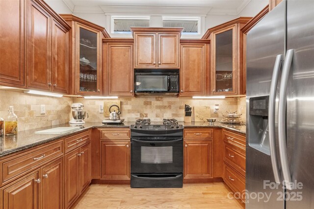 962 Blakeley Walk, Rock Hill, SC 29732 - kitchen featuring dark stone countertops, brown cabinets, black appliances, and light wood-style flooring