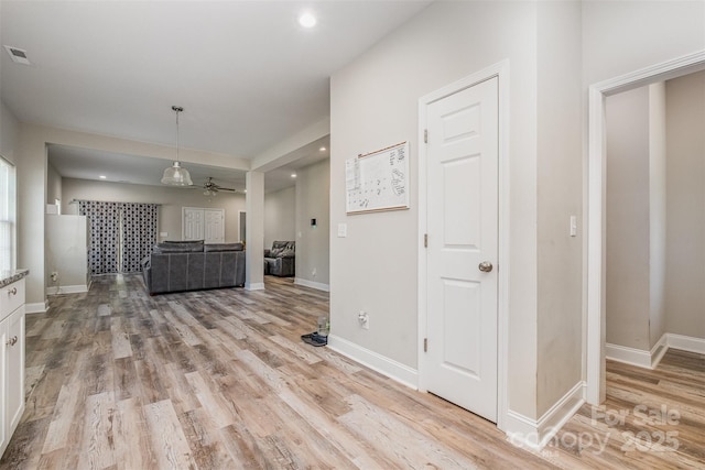 unfurnished living room with baseboards, light wood finished floors, ceiling fan, and visible vents