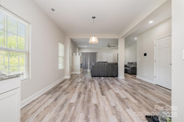 unfurnished living room with plenty of natural light, light wood finished floors, baseboards, and ceiling fan