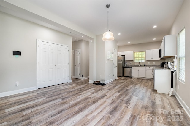 kitchen with light wood-type flooring, white cabinetry, recessed lighting, appliances with stainless steel finishes, and hanging light fixtures