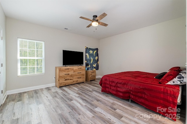bedroom featuring visible vents, baseboards, a ceiling fan, and wood finished floors