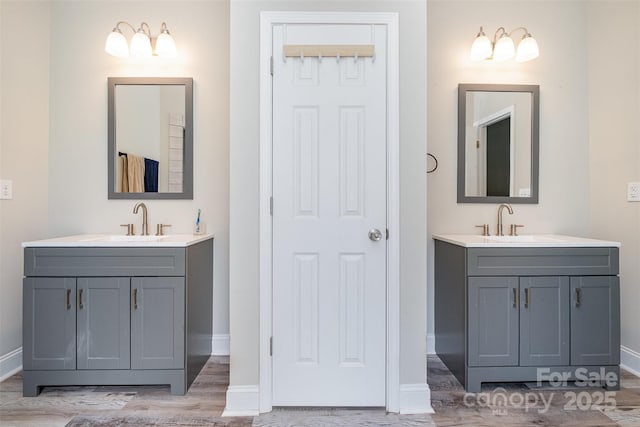 bathroom with a sink, baseboards, and two vanities