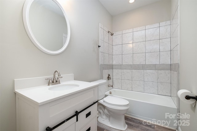 full bathroom with toilet, wood finished floors, vanity, and  shower combination