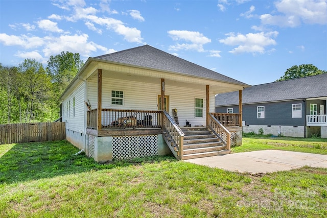 rear view of property featuring crawl space, a patio area, fence, and a lawn