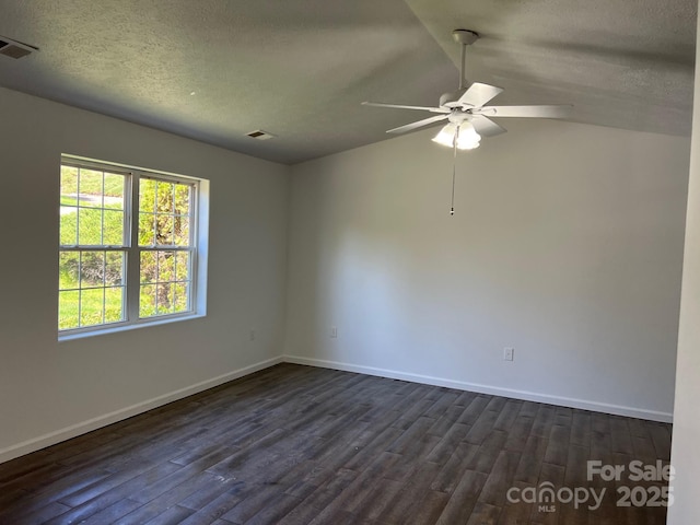 spare room with vaulted ceiling, a ceiling fan, baseboards, dark wood-style flooring, and visible vents