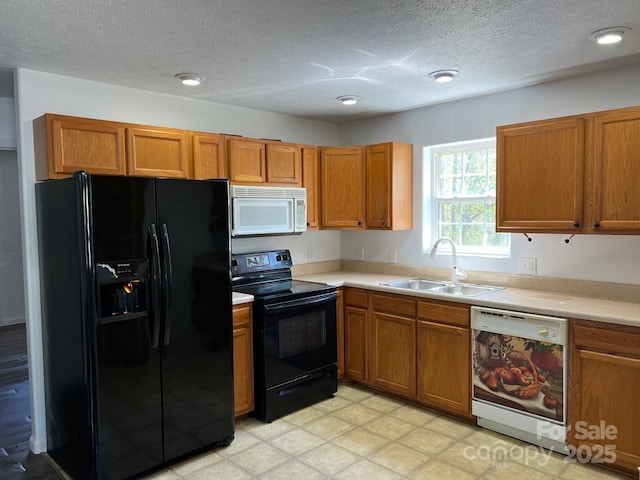 kitchen with a textured ceiling, black appliances, light countertops, a sink, and brown cabinets