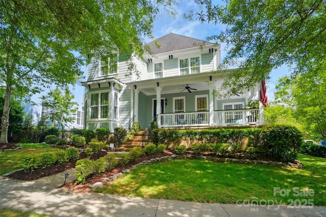 view of front of house with covered porch, ceiling fan, stairway, and a front yard