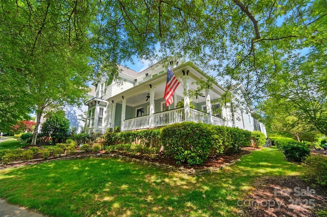 view of front of home with a porch, a ceiling fan, and a front yard