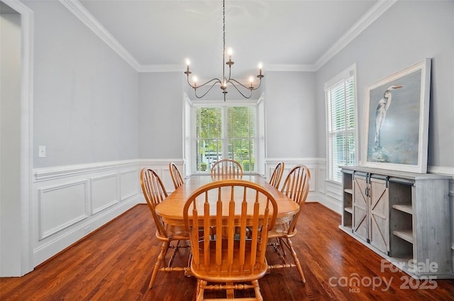 dining area featuring crown molding, a notable chandelier, wainscoting, a decorative wall, and wood finished floors