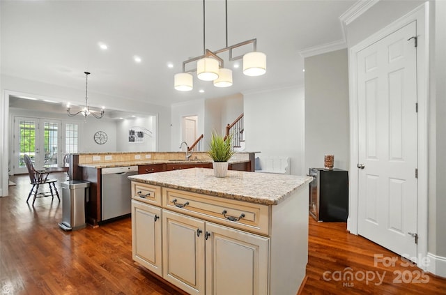 kitchen with crown molding, an inviting chandelier, a center island, cream cabinets, and dishwasher
