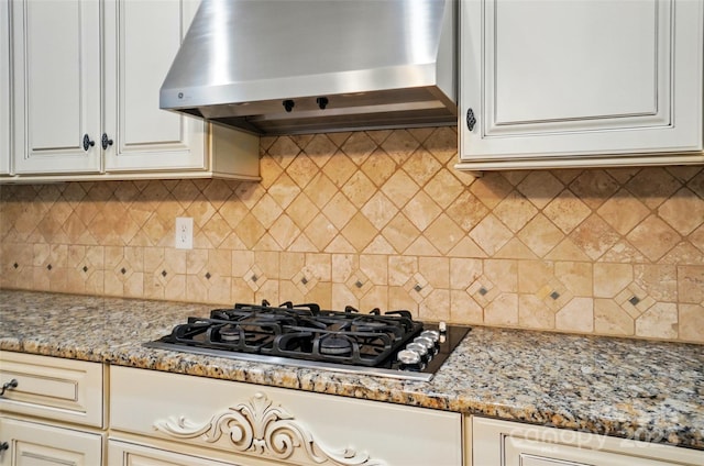 kitchen featuring gas cooktop, backsplash, light stone counters, and extractor fan