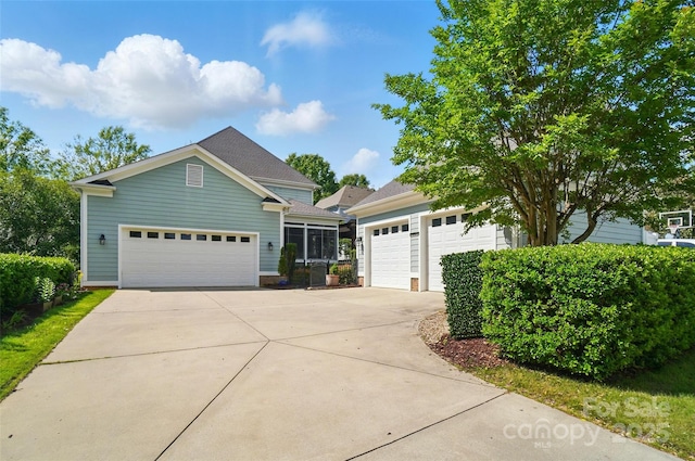 view of front of home with roof with shingles, an attached garage, and driveway