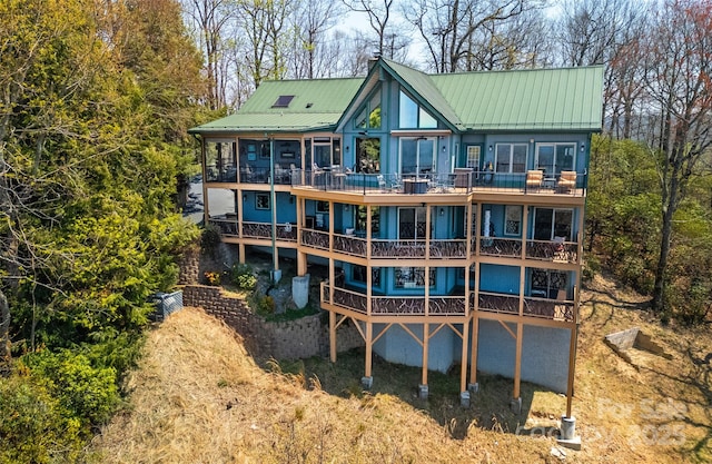 back of house featuring metal roof and a balcony