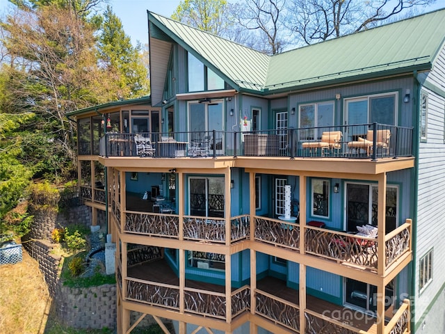 back of property with a standing seam roof, a sunroom, metal roof, and a balcony