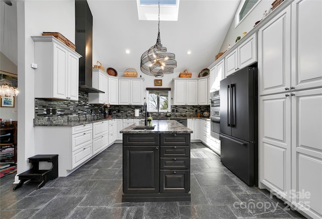 kitchen featuring oven, high quality fridge, wall chimney exhaust hood, backsplash, and a skylight